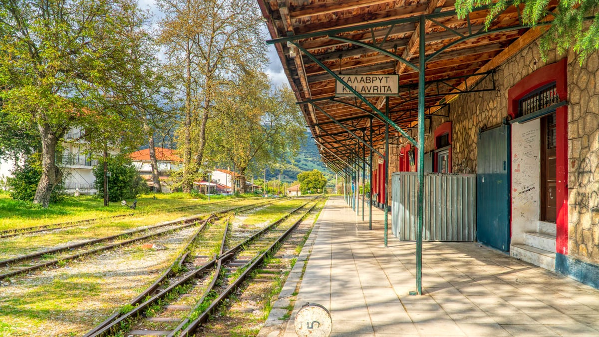 Charming view of Kalavryta railway station, featuring empty tracks and lush greenery in Greece.